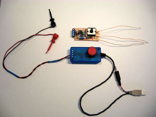 A fully-assembled 50:1 probe. A circuit board (with test-leads attached) is shown above the assembled probe. The probe described below has minor variations (the strain relief shown here is too expensive and does not do its job; the audio-plug's lead is longer; the search for a more attractive knob is in progress.)